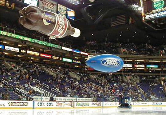 Coke a Cola and Bud Light blimps over ice rink.